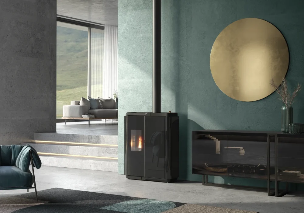 Rendering 3D ambientato di una stufa a pellet Slim AMG nera, posizionata contro una parete materica verde petrolio.